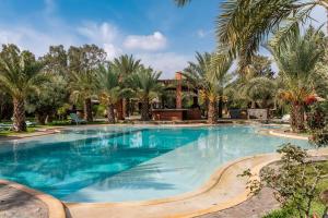 a large swimming pool with palm trees and a house at Domaine Alma Marrakech in Marrakech