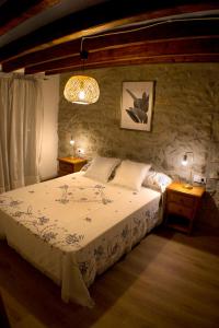 - une chambre avec un lit et un mur en pierre dans l'établissement Casa Palmira. Casa de pueblo con encanto, à Cervera del Maestre