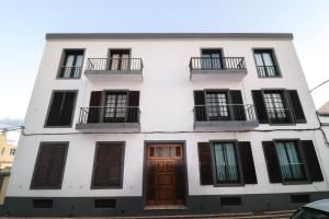 a white building with black windows and doors at Janela Mar VIP in Ponta Delgada