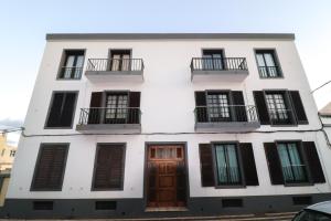 um edifício branco com janelas e portas pretas em Janela Mar VIP em Ponta Delgada