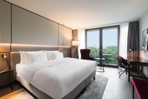 a large white bed in a hotel room with a window at Radisson Collection Hotel, Berlin in Berlin