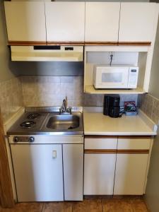 una pequeña cocina con fregadero y microondas en Stars Inn - Motel, en Fort Saskatchewan