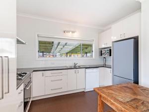 a kitchen with white cabinets and a wooden table at Southern Tides in Port Fairy
