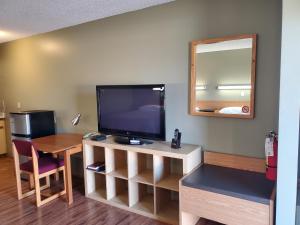 Habitación con TV, mesa y espejo. en Stars Inn - Motel, en Fort Saskatchewan