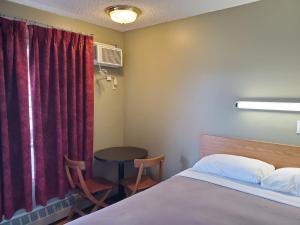 a bedroom with a bed and a table and a window at Stars Inn - Motel in Fort Saskatchewan