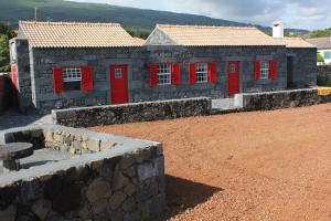 un edificio con puertas rojas y una pared de piedra en Adega Do Mirante, en São Roque do Pico