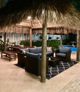 a resort patio with couches and a straw umbrella at Beach Aqualina Apartments in Fort Lauderdale