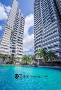 zwei hohe Gebäude mit Palmen vor einem Pool in der Unterkunft Meridin Medini @ JB City Homestay in Johor Bahru