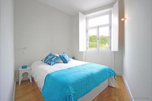 a bedroom with a bed with blue sheets and a window at Oporto River and Ribeira Views in Vila Nova de Gaia