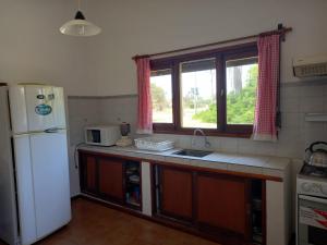 uma cozinha com um frigorífico branco e um lavatório em Chalecito hermoso em La Paloma