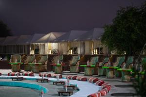 a group of chairs and tables and a pool at night at Heritage Juma Resort with swimming pool in Jaisalmer