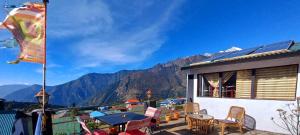 balcón con mesa, sillas y montañas en Lama Hotel - Cafe De Himalaya en Lukla