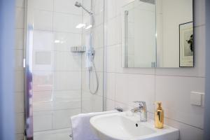 a white bathroom with a sink and a shower at Stadthaus Sinfonia in Baden-Baden