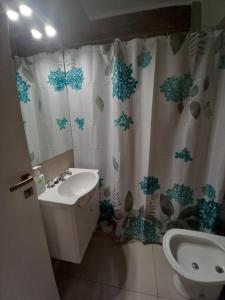 a bathroom with a sink and a toilet and a shower curtain at 2 ambientes en Playa Grande Matheu y Alem in Mar del Plata