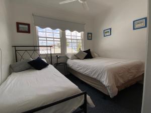 two beds in a room with a window at Allamanda House, 3 Willow Street in Crescent Head