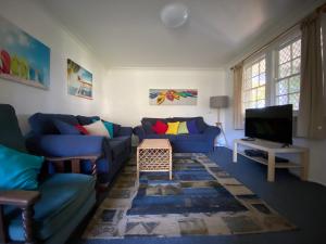 新月岬的住宿－維洛街3號阿拉曼達度假屋，客厅配有蓝色的沙发和电视