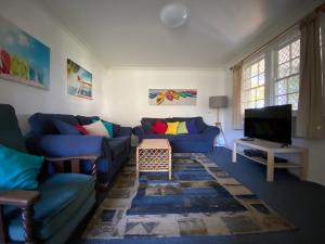 a living room with blue couches and a tv at Allamanda House, 3 Willow Street in Crescent Head