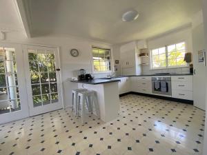 a kitchen with white cabinets and a checkered floor at Allamanda House, 3 Willow Street in Crescent Head