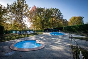 two swimming pools on a patio with trees in the background at Appartamento Roero cottage 3 in Alba