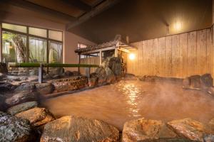 a pool of water in a room with rocks at Arima Onsen Tocen Goshobo in Kobe