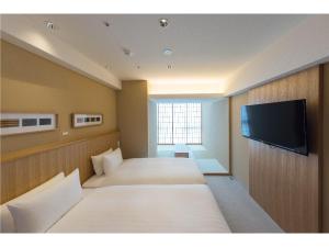 a room with two beds and a flat screen tv at 9 HOTEL Hakata in Fukuoka