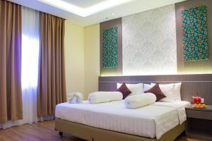 1 dormitorio con 1 cama grande con almohadas blancas en Nevada Ketapang Hotel en Ketapang