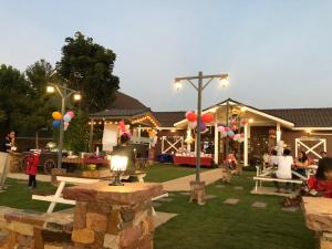a group of people sitting in a yard with balloons at The Green Land Farm in Si Khio