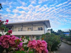 Uma casa branca com flores cor-de-rosa à frente. em Beyond Island em Moalboal