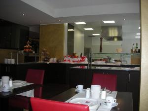 un restaurante con una mesa con sillas rojas y una cocina en Hotel Herzblut - Joker card included in summer, en Saalbach Hinterglemm