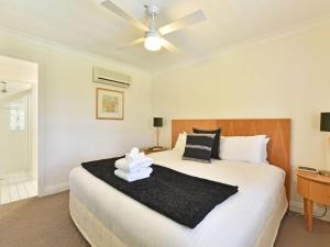 a bedroom with a large bed with a ceiling fan at Villa 2br Heafy Lodge Villa located within Cypress Lakes Resort in Pokolbin