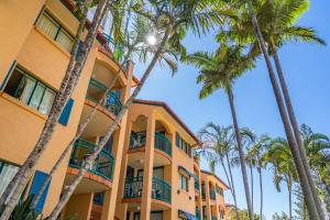 un bâtiment avec des palmiers en face de celui-ci dans l'établissement Aruba Sands Resort, à Gold Coast