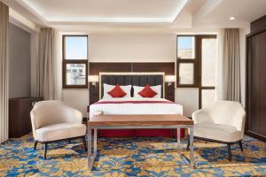 a hotel room with a bed and two chairs at Ramada Hotel & Suites by Wyndham Yerevan in Yerevan