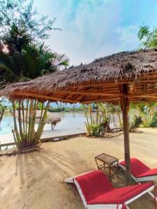 zwei Stühle und ein Strohschirm am Strand in der Unterkunft Sabay Beach in Kampot