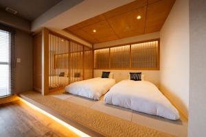 2 letti in una camera da letto con una grande finestra di Wayfarer Kyoto Shijo a Kyoto