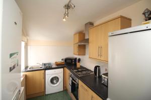 a kitchen with a stove top oven next to a washer at 2 bed flat, Cambuslang, Glasgow, free parking in Cambuslang