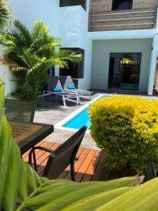 a patio with a table and chairs and a pool at Coconut Groove in Grand-Baie
