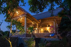 a house with a thatched roof and a blue chair at Sanglung Villas & Suites in Kubutambahan