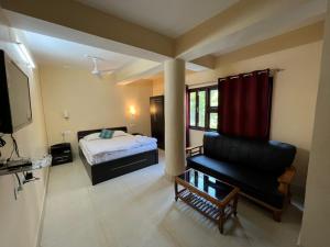 a bedroom with a bed and a couch and a television at Hotel Cymbidium Residency in Tādong