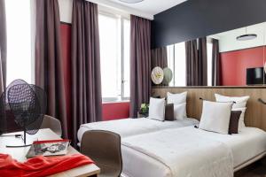 2 letti in una camera d'albergo con pareti rosse di Hôtel Opéra Liège a Parigi