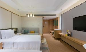 a hotel room with a bed and a flat screen tv at Holiday Inn Chongqing Guanyinqiao, an IHG Hotel in Chongqing