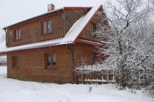 a wooden house with snow on the roof at Gospodarstwo Agroturystyczne Bobrowa Zagroda in Narewka