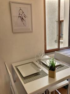 a white table with a plate and glasses on it at Studio vue sur la roche, au calme Moustiers #1 in Moustiers-Sainte-Marie