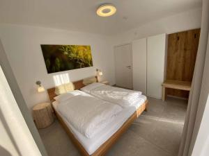 una camera da letto con un grande letto con lenzuola bianche di Ferienhaus AUSZEIT a Crottendorf