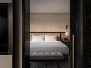 Un dormitorio con una cama blanca con un banco. en Empark Prime Hotel Beijing, en Beijing