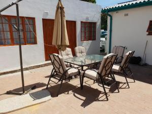 a glass table with chairs and an umbrella on a patio at Fama Lodge Single Rooms in Cape Town