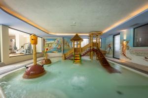 a childrens play room with a slide and a play area at Alpholiday Dolomiti Wellness & Family Hotel in Dimaro