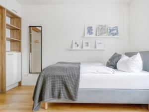 a white bedroom with a bed and a mirror at limehome Augsburg Am Katzenstadel in Augsburg