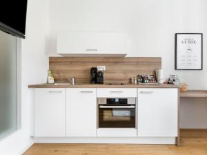 a kitchen with white cabinets and a sink at limehome Augsburg Am Katzenstadel in Augsburg