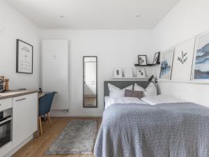 a white bedroom with a bed and a desk at limehome Augsburg Am Katzenstadel in Augsburg