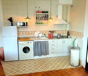 uma cozinha com uma máquina de lavar roupa e um lavatório em Luminoso con vistas y chimenea apto mascotas em Benaocaz
